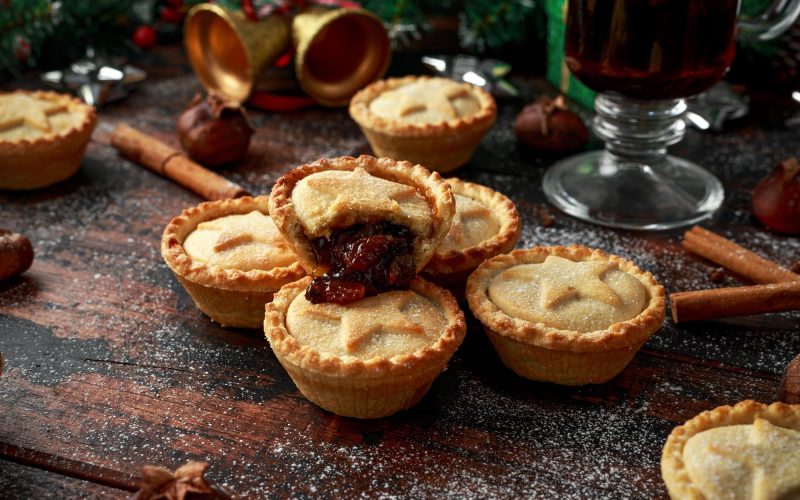 British Christmas mince pies with decoration, gifts, green tree branch on wooden rustic table